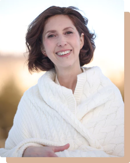 Muriel Joubert, coach professionnel, souriante les bras croisés avec un gilet blanc sur elle.