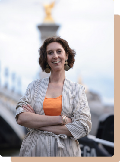 Contactez Muriel Joubert, coach professionnelle, souriante, en tenue claire, bras croisés, devant le pont Alexandre III à Paris